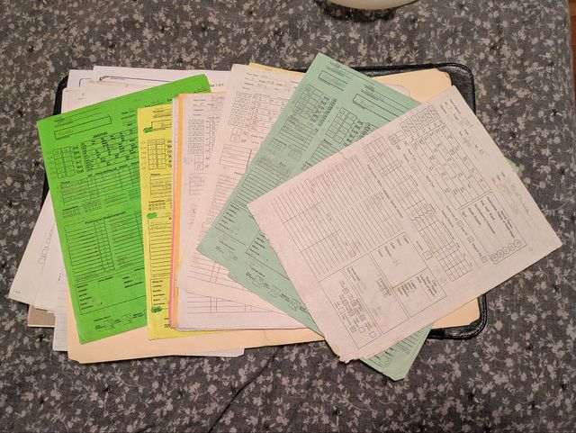 A pile of white and colored character sheets for AD&D 2nd Edition, fanned out