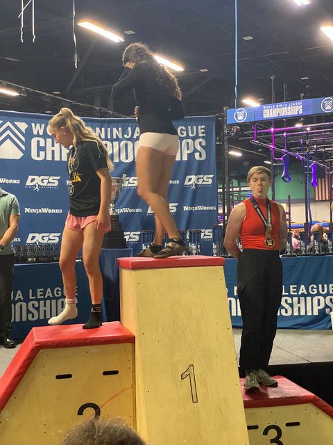 A world class athlete sticking her tongue out at her father from atop the podium after accepting a bronze medal.  "Daaaaaaaaad that's enough photos!"